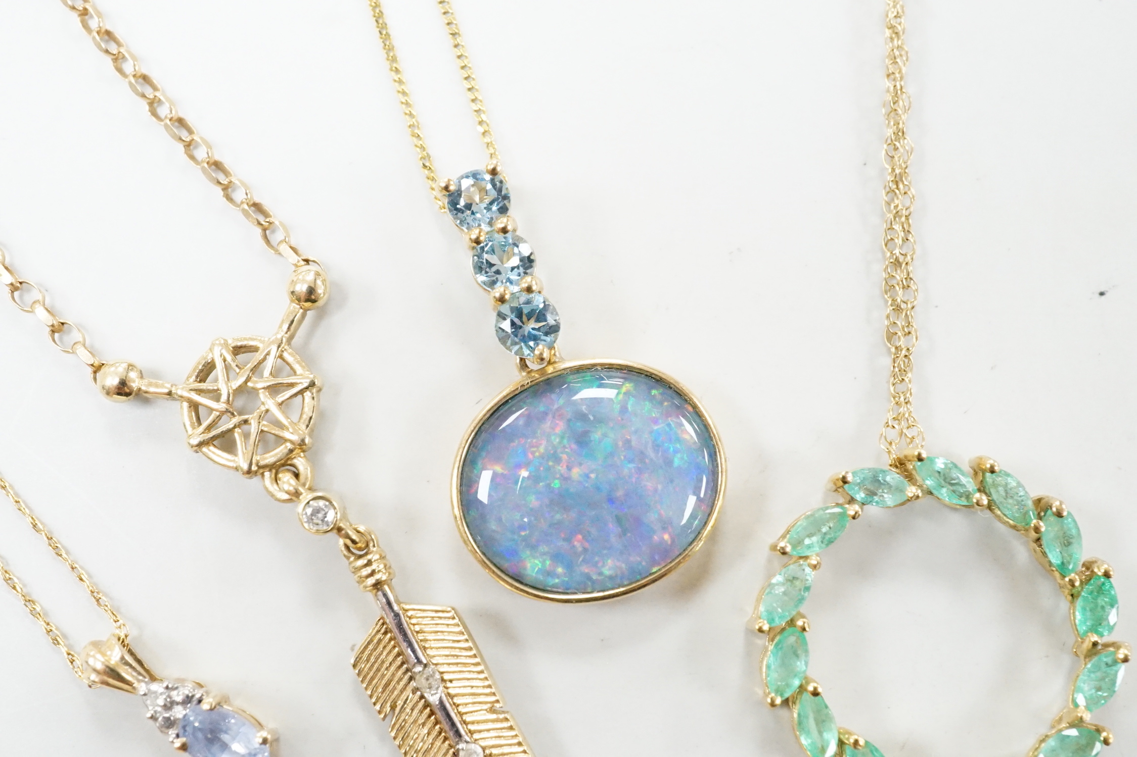 Three assorted modern 9ct or yellow metal and gem set pendants, on 9ct chains including opal doublet and blue topaz, feather shape and emerald set circular and a similar 10k pendant, on a 10k chain, longest 52cm, gross w